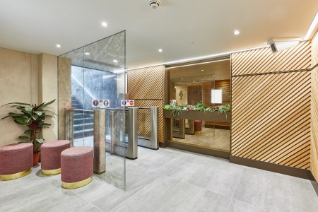 Princesshay Shopping Centre public toilets, Exeter - wooden panelling by entrance/exit with seating area and large plant, grey tiled floor