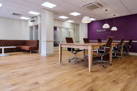 Winkworth Estate Agents, Crystal Palace - interior featuring wooden flooring, wooden desk and office chairs, purple wall with logo and brown leather bench seating area