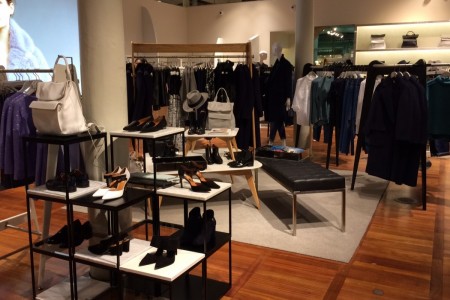 Whistles, St Pancras Station, London - wooden flooring, shoe displays on black and white shelving, clothes displays behind 
