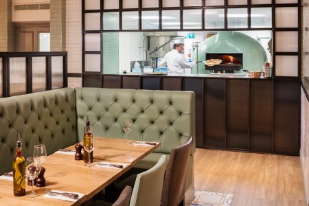 Wildwood, Crawley - blue leather booth seating with kitchen area behind 