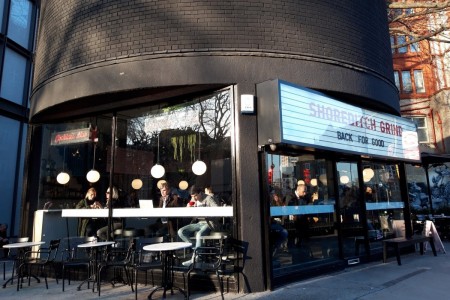 Shoreditch Grind, London - black brick exterior with branding over doors, outdoor seating