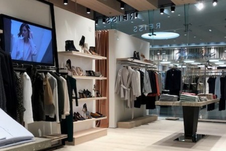 Reiss, Canary Wharf - tv screen with advertising and wooden shelving surrounding it