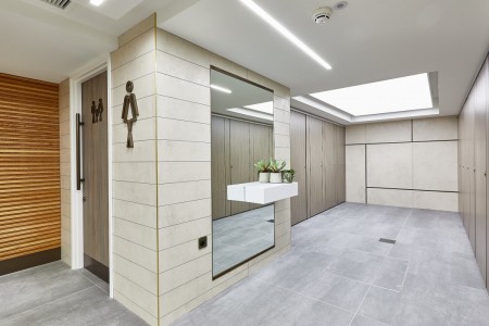 Princesshay Shopping Centre public toilets, Exeter - beige tiling on walls, large floor length mirror with shelf and plants, grey floor tiling