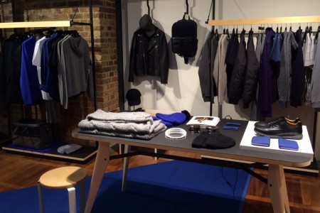 Whistles, St Pancras Station, London - black table with shoes hats, scarves, clothing displays hanging behind and exposed brick wall