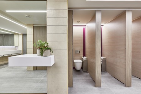 Princesshay Shopping Centre public toilets, Exeter - beige tiling on walls, large floor length mirror with shelf and plants, grey floor tiling, stall doors open to show toilets