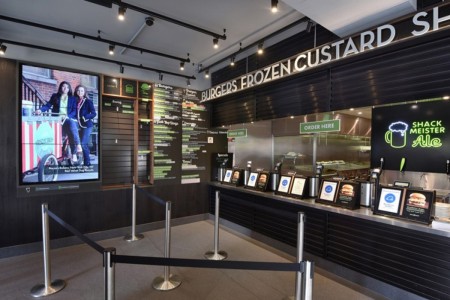 Shake Shack, Leicester Square - till area with dark cladding around and menu on the wall with green and white writing
