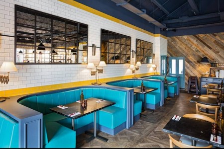 Wildwood, Braintree - blue booth seating, white and yellow tiled wall behind and wooden flooring