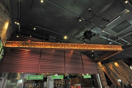 Shake Shack, New Oxford Street, London - branding over point of sale area, sign with food names, wooden cladding on walls and exposed brickwork
