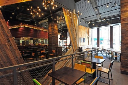 Shake Shack, New Oxford Street, London - wooden clad walls with exposed brick work, kitchen area, stools and tables
