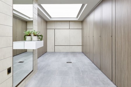Princesshay Shopping Centre public toilets, Exeter - beige tiling on walls, large floor length mirror with shelf and plants, grey floor tiling, wooden walls for stalls
