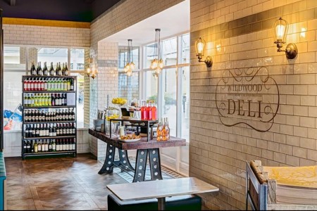 Wildwood, Braintree - white tiled walls with logo, wooden bench with food and drink products on in front of window